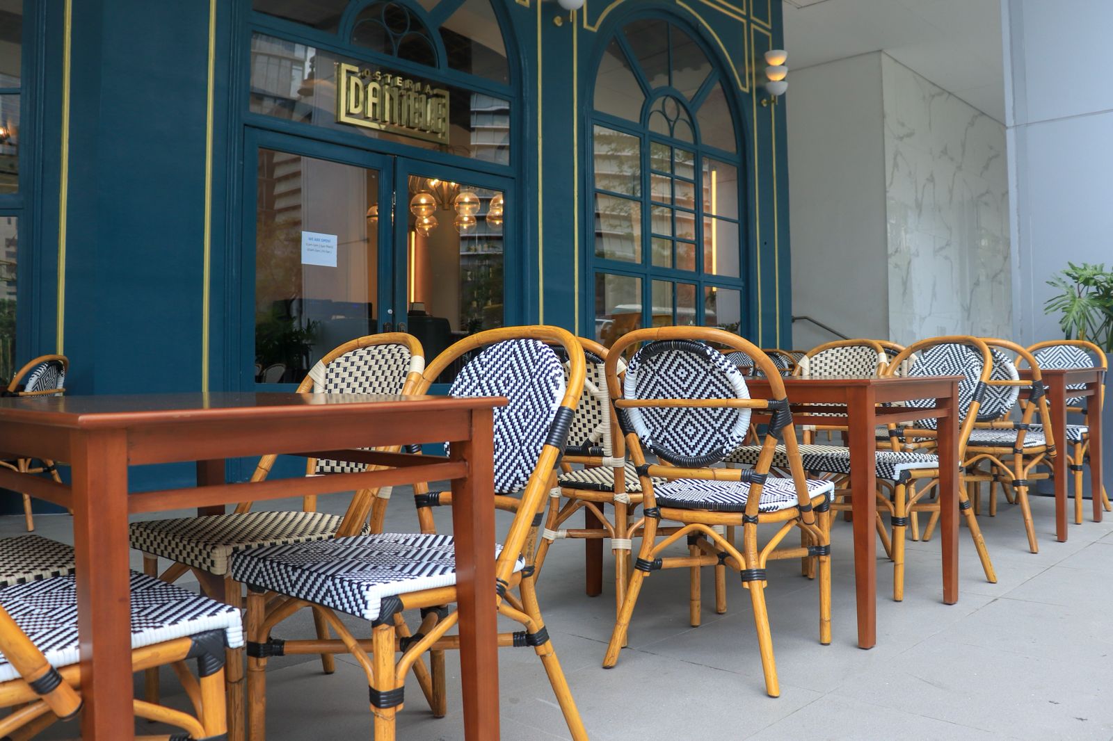 Black-and-white woven bistro chairs arranged around wood tables outside a restaurant.
