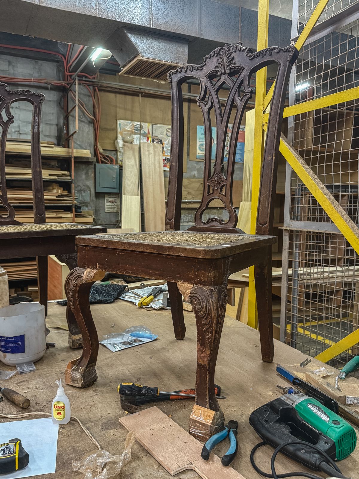 Ornate carved chair on a workshop bench during careful restoration work.