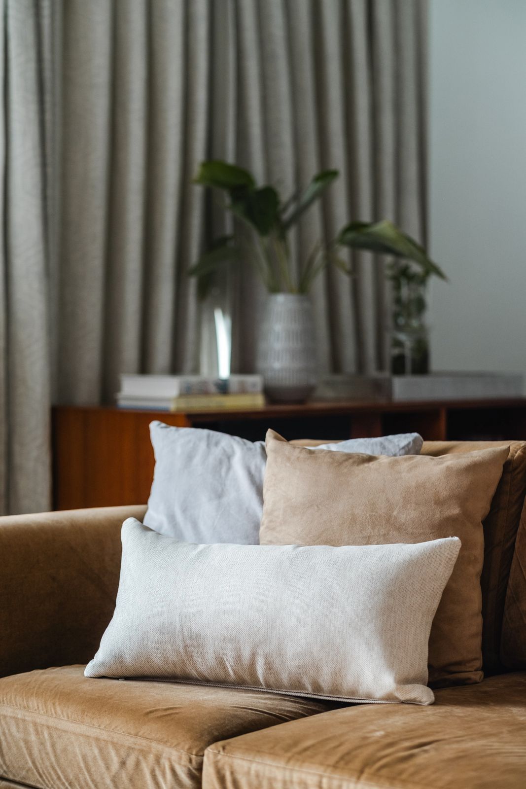 Layered neutral pillows and cushions arranged on a tan sofa.
